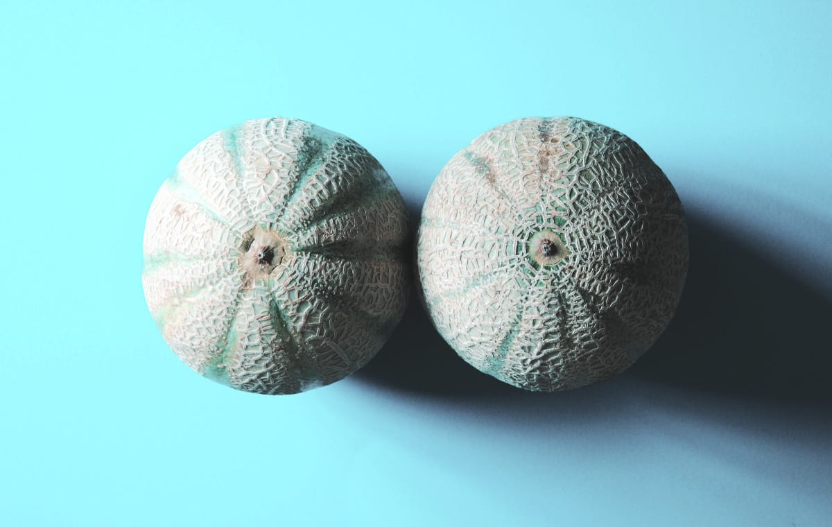 Two round melons placed beside each other suggestive of breasts